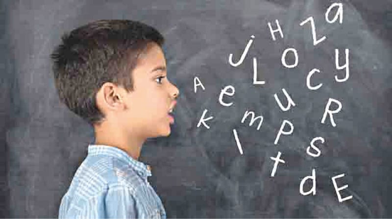छोटा मुलगा शाळेत भाषिक अक्षरे उच्चारत आहे, ज्यामुळे त्याच्या भाषा आणि साक्षरता विकासाचा दाखला मिळतो.