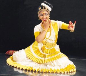 भारतीय पारंपरिक नृत्य सादर करत असलेली युवती, निळ्या आणि पांढर्या रंगाच्या पारंपरिक पोशाखात, सुंदर अभिव्यक्ती.
