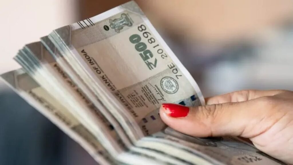 A hand holding a bundle of Indian 500 rupee currency notes.
